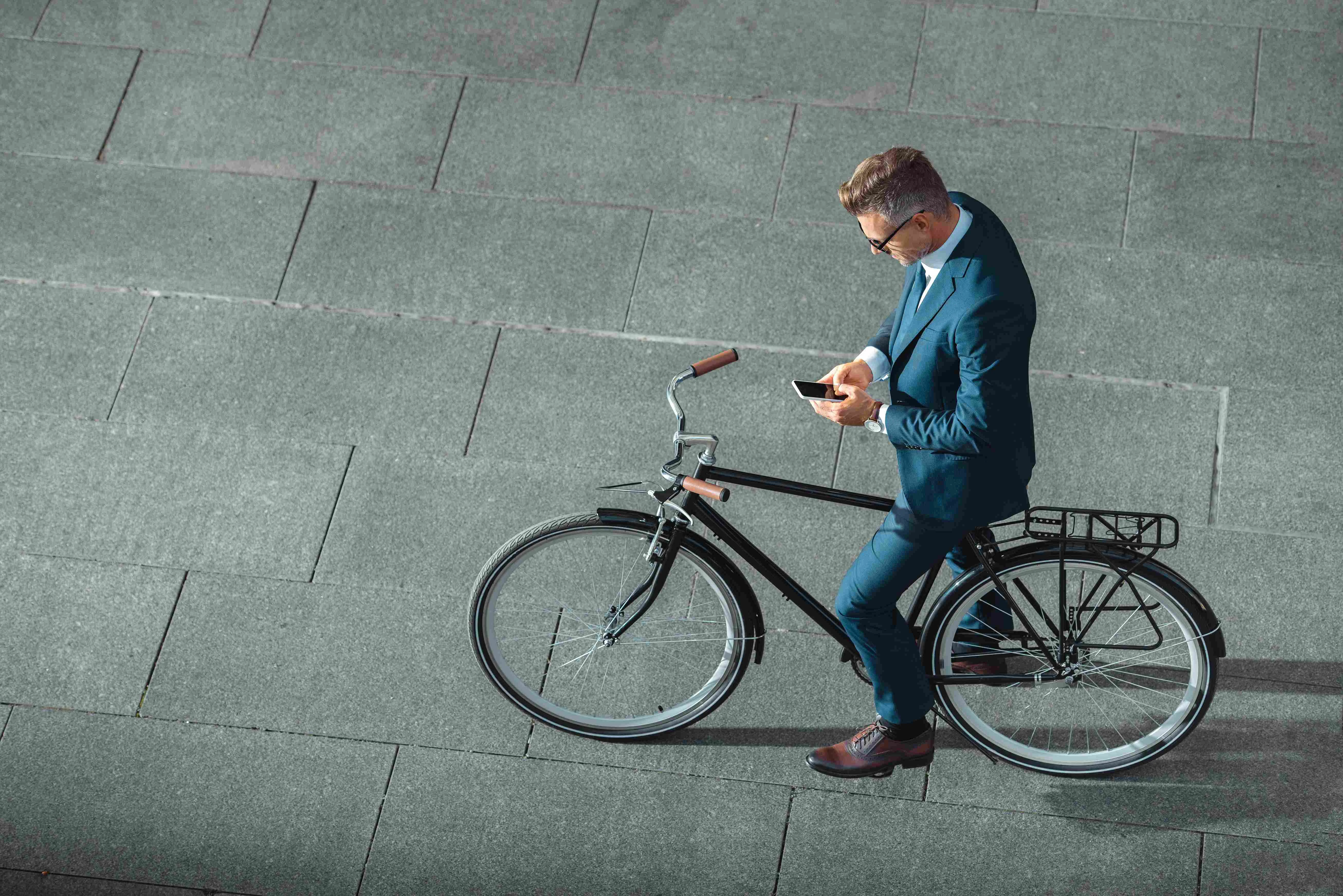 Mitarbeiter von Bornhauser People's Management Headhunter Schweiz und Personalberatung Schweiz und executive search sitz auf Citiybike und liest emails auf Handy von oben fotographiert 