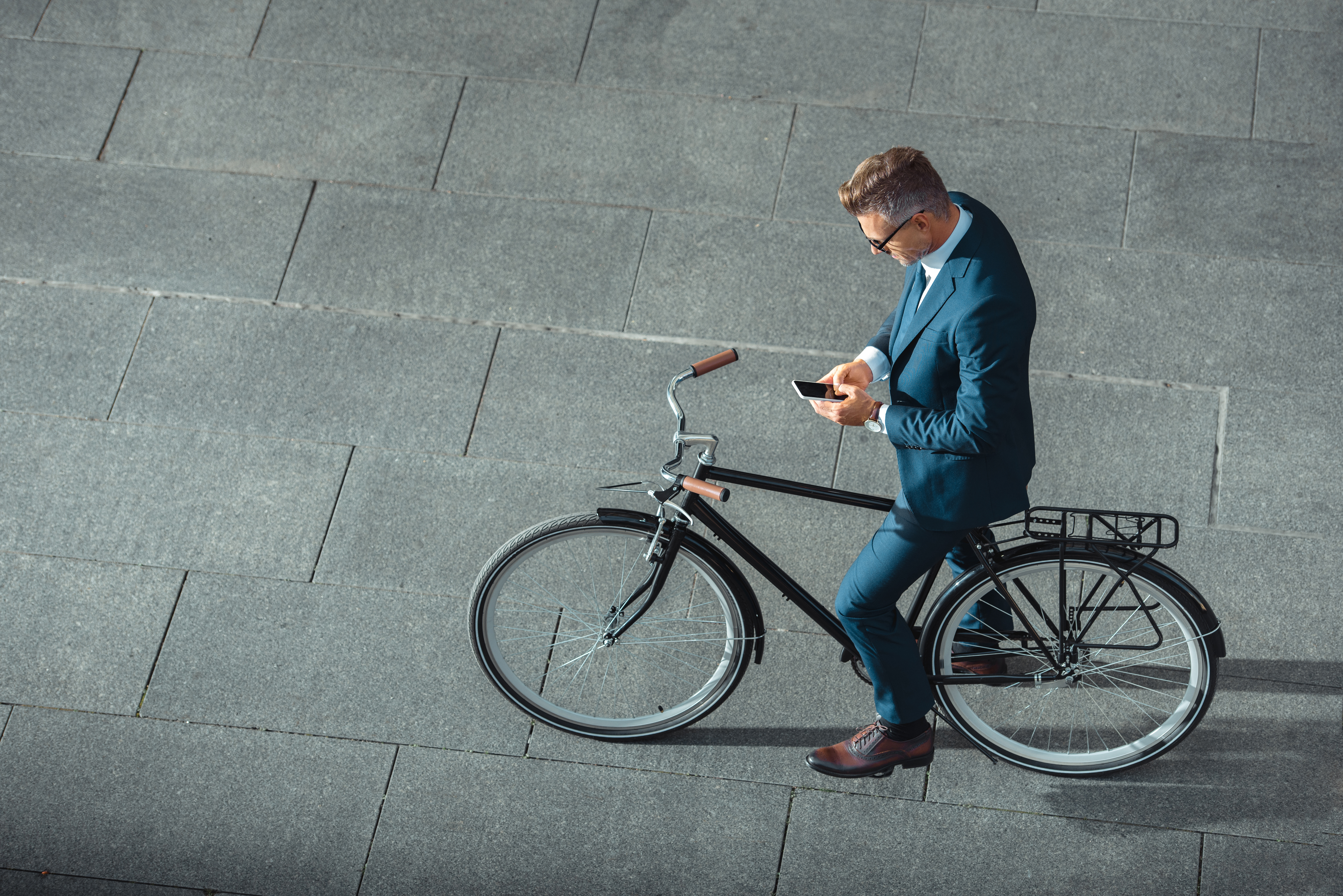 Mitarbeiter von Bornhauser People's Management Headhunter Schweiz und Personalberatung Schweiz und executive search sitz auf Citiybike und liest emails auf Handy von oben fotographiert