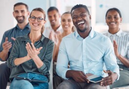 Team von SAP Zürich sitzt in einer Präsentation und lacht und applaudiert 