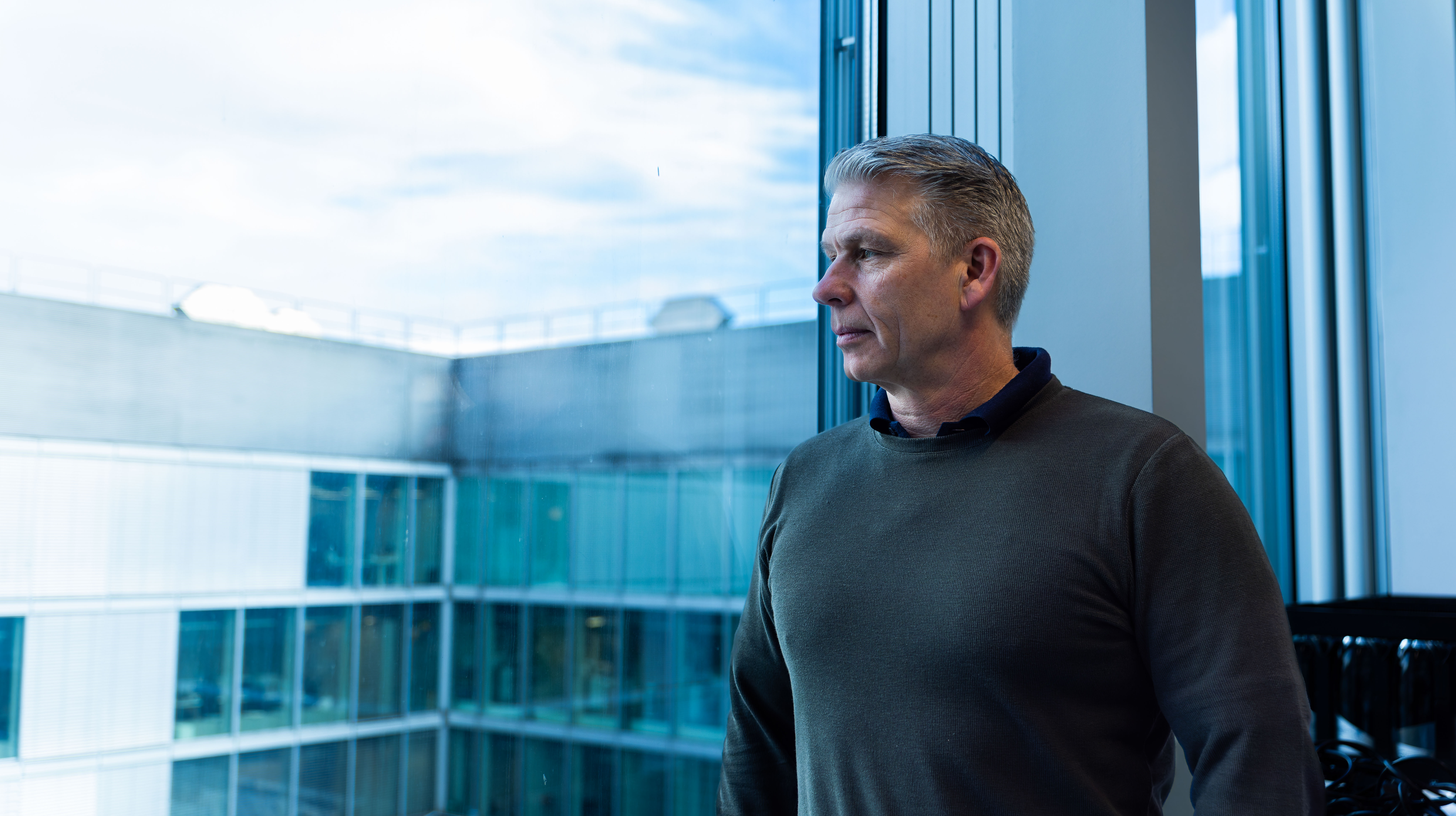 Selbstsicherer Business Mann steht am Fenster vor seinem Team von top Headhunter Zürich