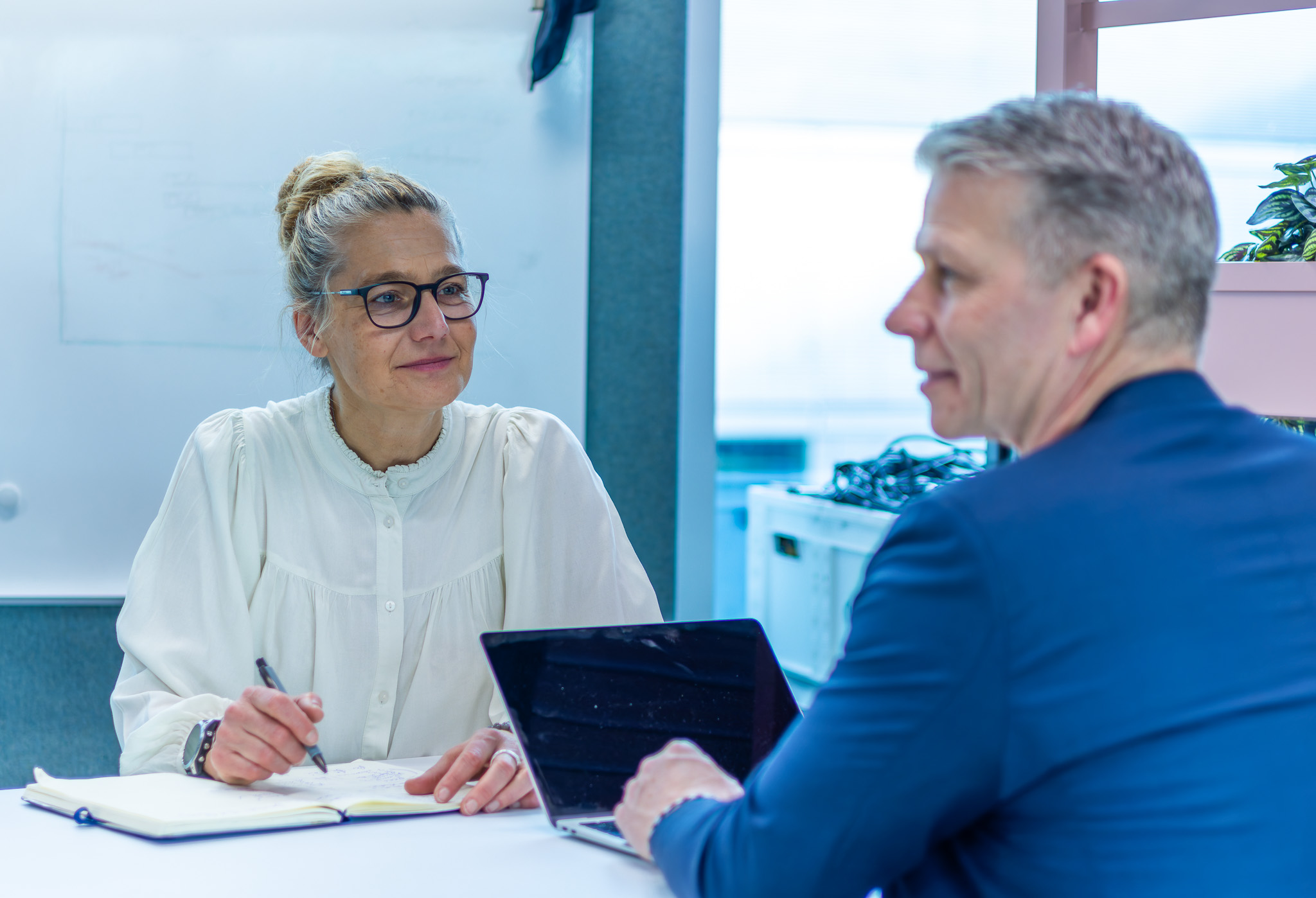 Business Frau mit lockerer Bluse schaut zufrieden lächelnd zum Headhunter SAP in den Büros von Bornhauser Peoples Management