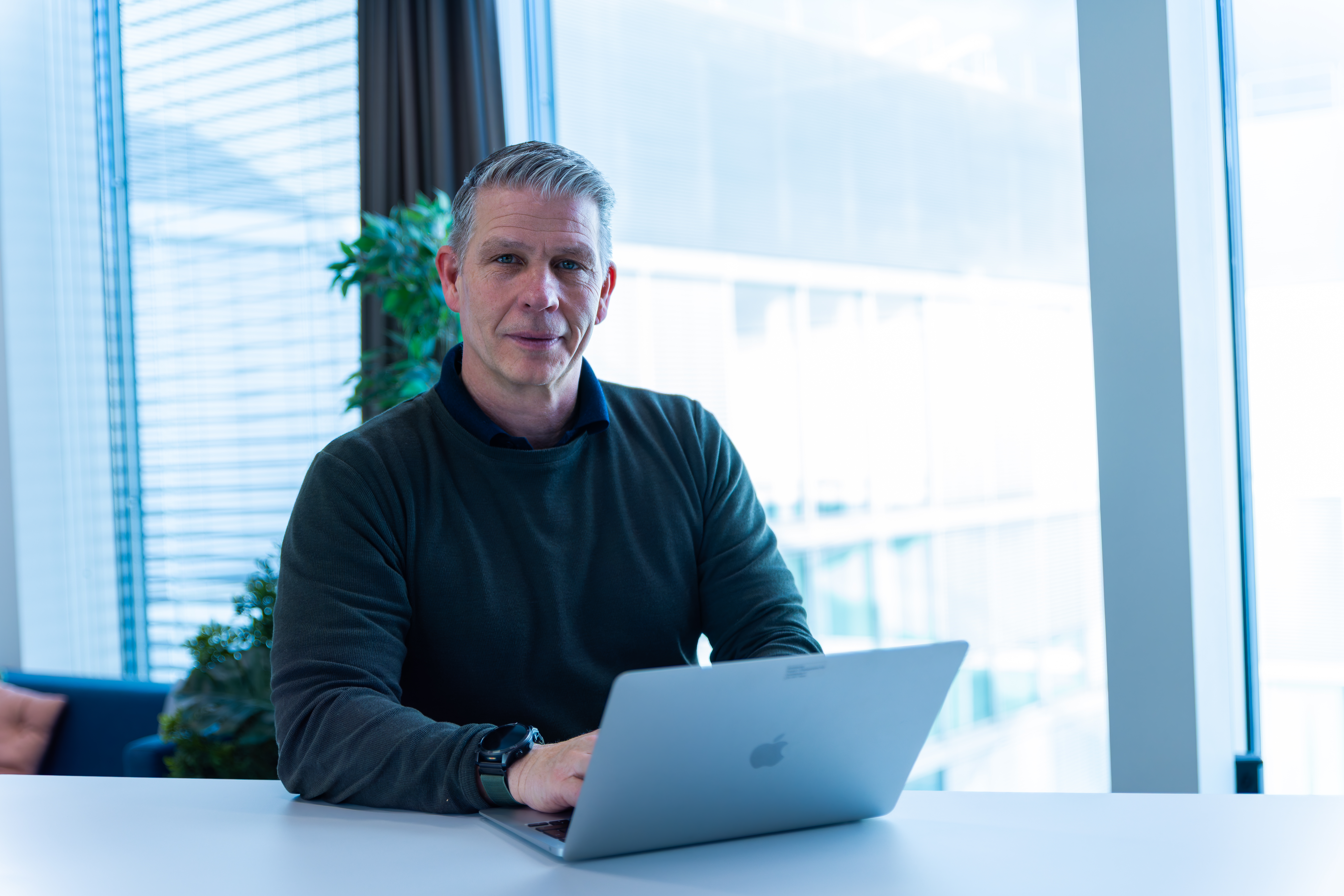 Selbstsicherer Business Mann sitzt am Fenster vor seinem Team von top Headhunter Biel/ Bienne
